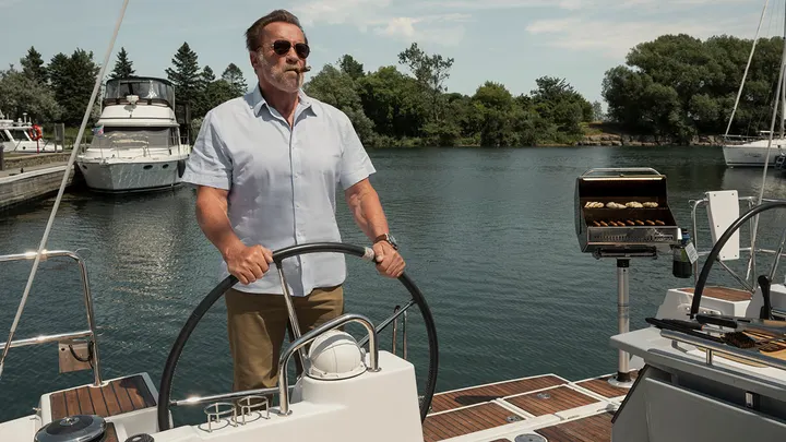 Arnold Schwarzenegger is seen smoking a cigar while driving a boat in a photo from "FUBAR." (Christos Kalohoridis/Netflix)
